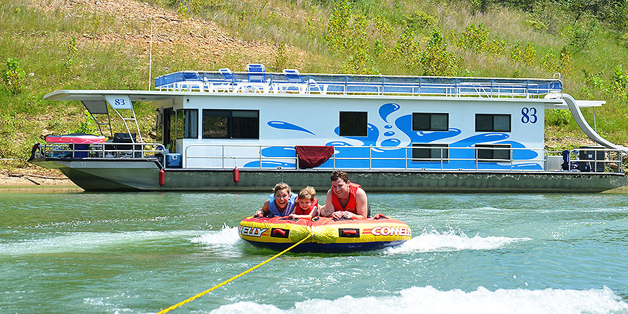 Family being pulled behind the houseboat on a float.