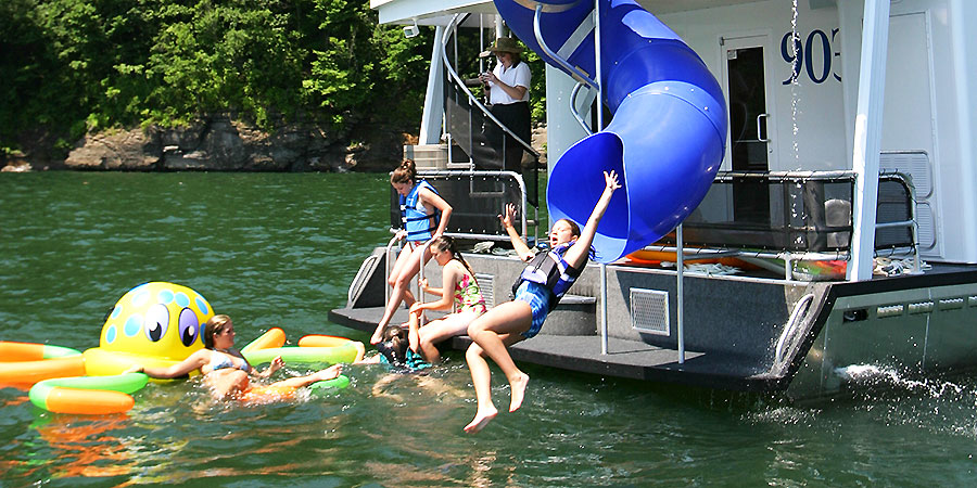 Kids having a great time on the water slide that attached to the houseboat.