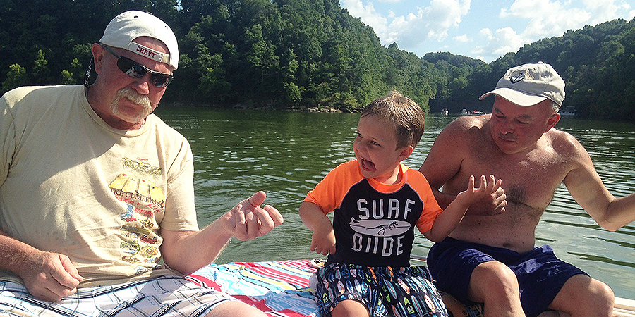 Grandpa, father and son playing the air guitar while hanging out at the lake.
