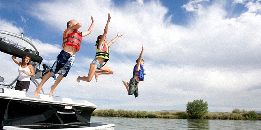 Kids jumping off the die of the boat into the lake.